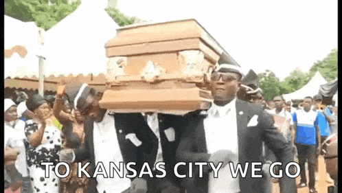 a group of men are carrying a coffin in a cemetery and dancing .