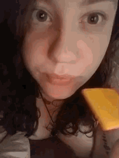 a close up of a woman 's face with a piece of cheese in her hand .