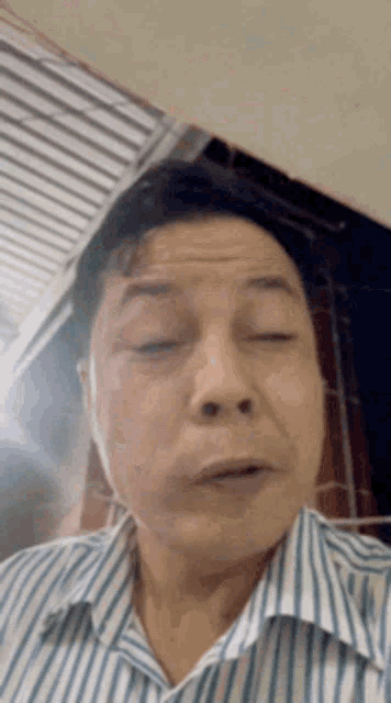 a man in a blue and white striped shirt is making a funny face