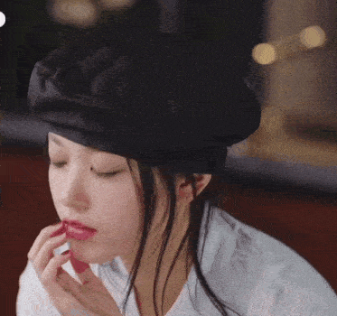 a woman wearing a black beret and a white shirt eating something