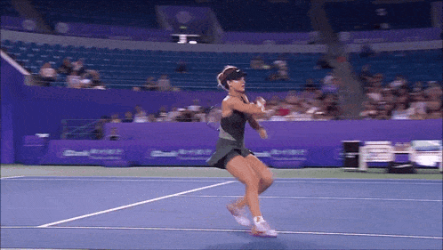 a woman in a black dress is playing tennis