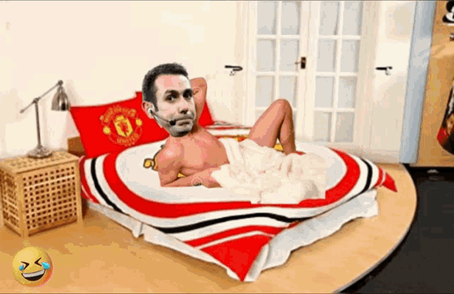 a man laying on a bed with a manchester united blanket on it