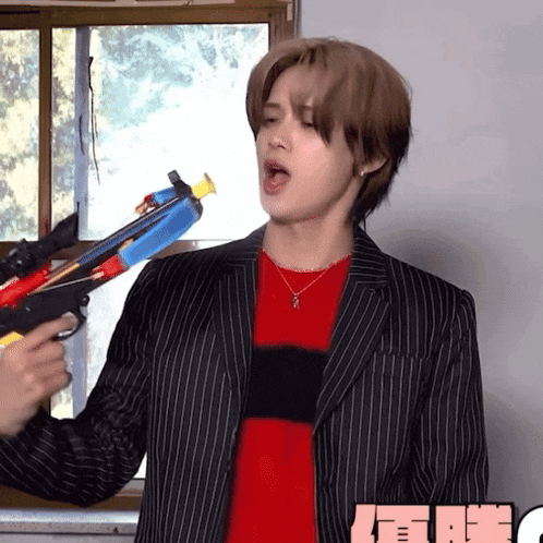a man in a striped suit is holding a toy gun in his hand