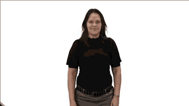 a woman wearing a black shirt and gray jeans holds up her hand