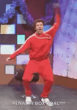 a man in a red outfit is jumping in the air with the words penalty box goal written below him