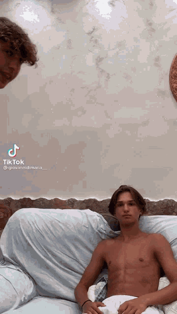 a man without a shirt is laying on a couch with a tiktok video behind him