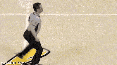 a referee is walking on a basketball court while a player throws a basketball .