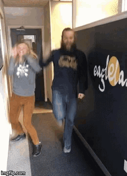 a man and a woman are dancing in a hallway in front of a wall that has the word eagle on it