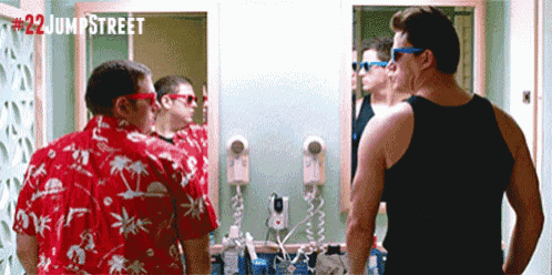 two men are standing in front of a bathroom mirror with the number 22 jump street written on the bottom