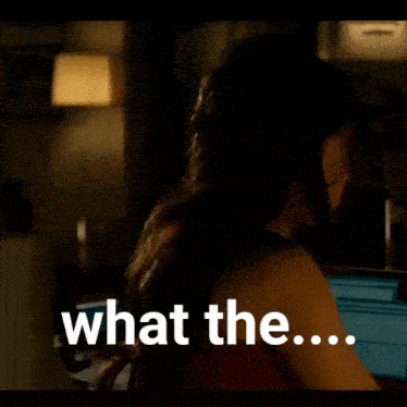a woman in a dark room with the words what the on the bottom right