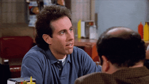 a man in a blue shirt talks to another man in a restaurant