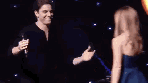a man and a woman are dancing on a stage in front of a light .