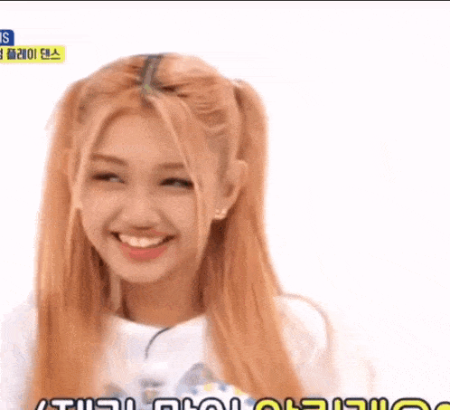 a girl with blonde hair and pigtails is smiling and looking at the camera .