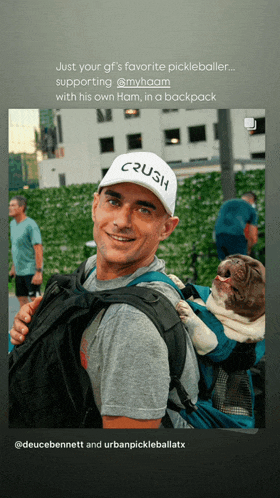 a man wearing a hat that says crush is carrying a dog