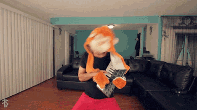 a man is holding a guitar in a living room with a dollar sign on the floor