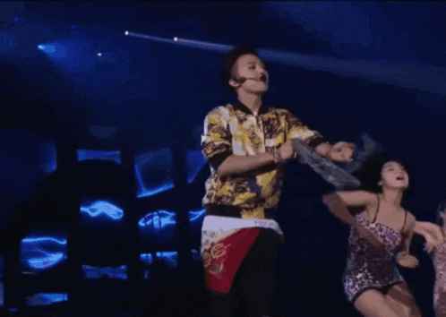 a man and a woman are dancing on a stage and the man is giving the middle finger