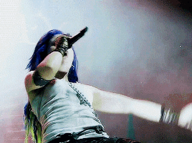 a woman with blue hair is singing into a microphone on stage