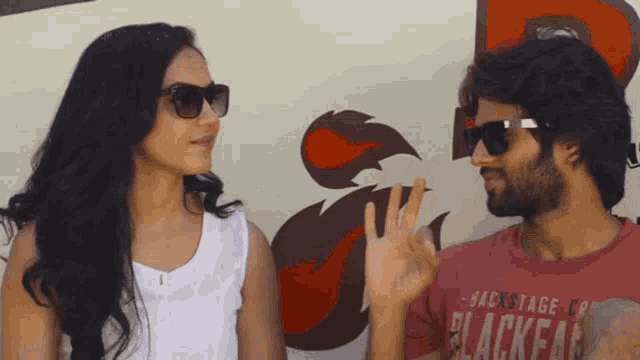 a man wearing a red shirt that says blackfan waves to a woman