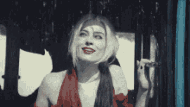 a woman in a red dress is standing in the rain looking up .