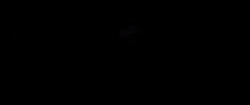 a person is standing in a dark room next to a coffin with a light on it .