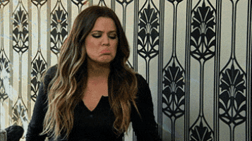 a woman with long hair is making a funny face in front of a wall with a patterned wallpaper .