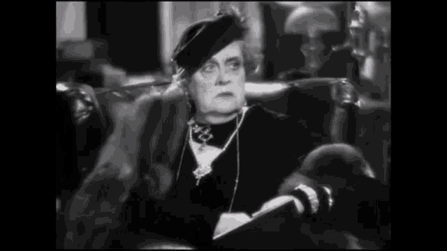 a black and white photo of a woman sitting in a chair .