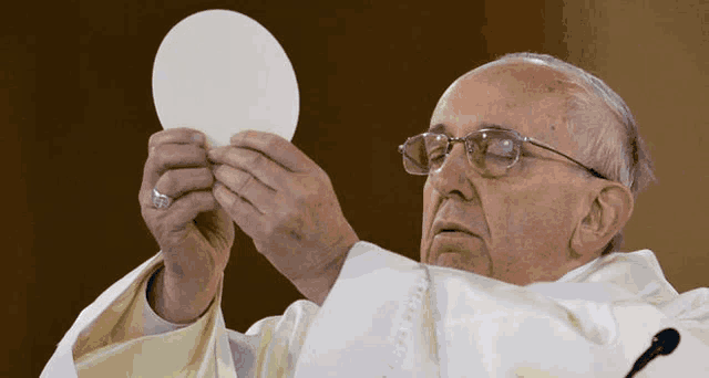 a man in a white robe holds a white circle in his hands