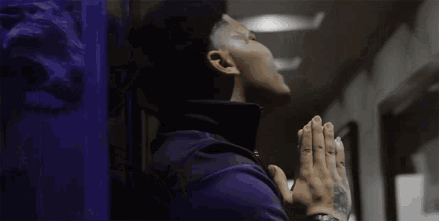 a man with a tattoo on his arm is praying