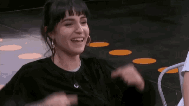 a woman is sitting in a chair and smiling with her hands in the air