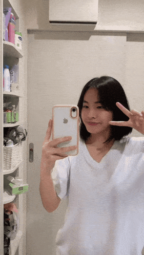 a woman in a white shirt is taking a picture of herself in a mirror
