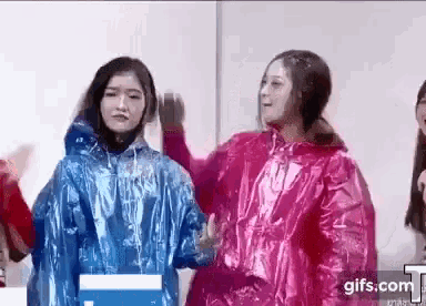 two women are standing next to each other wearing plastic raincoats .