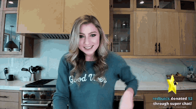 a woman in a kitchen wearing a good vibes sweater