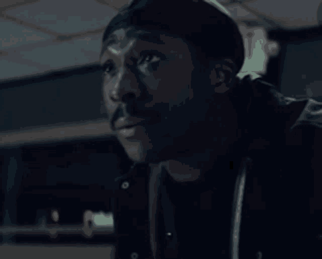 a man with a mustache is wearing a black jacket and a black beanie .