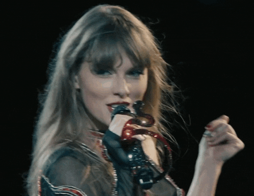 a woman is singing into a microphone with a red bracelet around her wrist