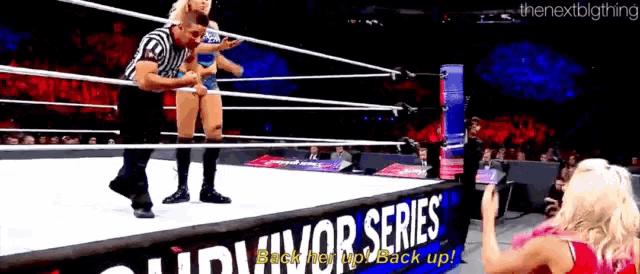 a woman is taking a picture of a wrestler in a wrestling ring with a sign that says survivor series