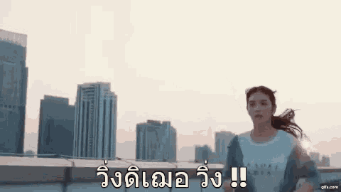 a woman is running on top of a building in front of a city skyline .