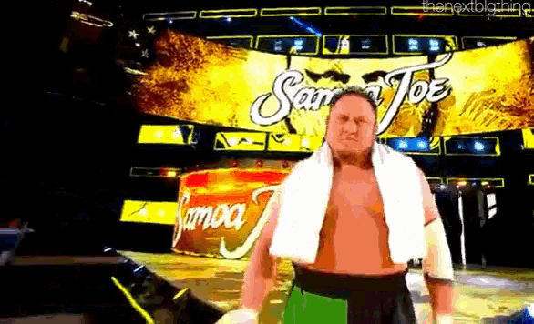 a wrestler with a towel around his neck stands in front of a banner that says samoa