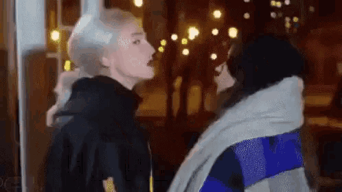 a couple of women are standing next to each other in front of a window .