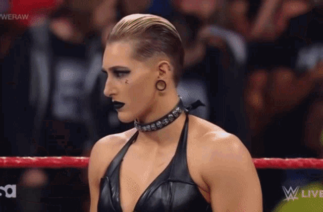 a woman is standing in a wrestling ring wearing a choker .