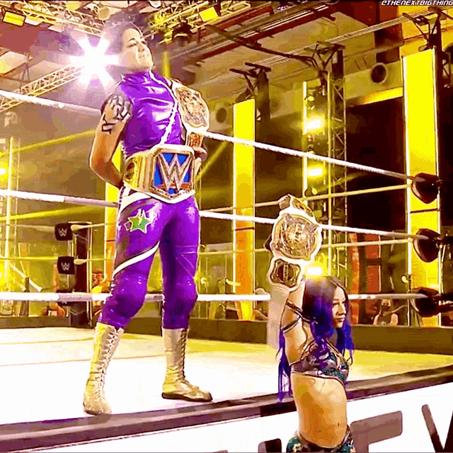 a wrestler in a purple outfit is holding a wrestling championship belt