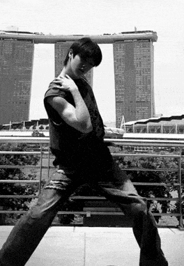 a black and white photo of a man standing in front of a tall building