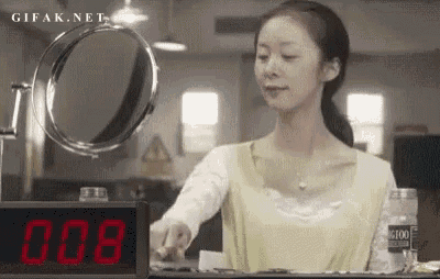 a woman is standing in front of a mirror and a digital clock with the number 008 on it .