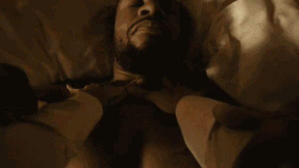 a man with a beard is laying in a bed with his hands on his chest