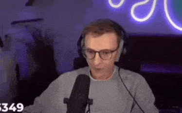 a man wearing glasses and headphones is sitting in front of a microphone .