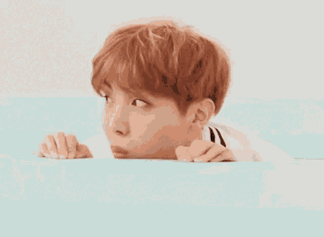 a young man with red hair is laying in a bathtub .