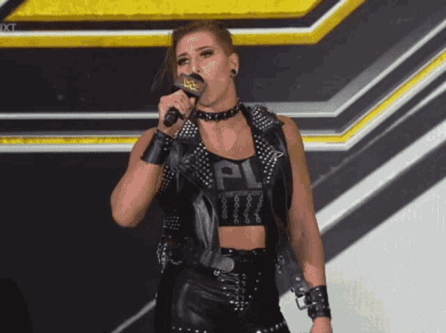 a woman is singing into a microphone while wearing a crop top that says " pl "