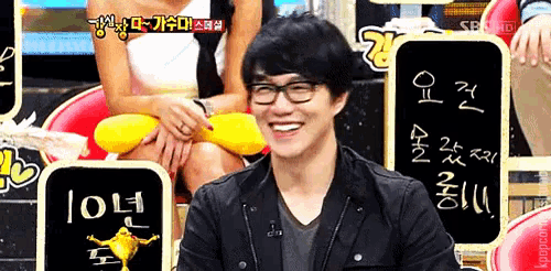 a man wearing glasses is smiling in front of a sign that says ' 10 '