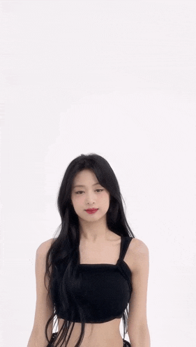 a woman in a black crop top and black skirt is giving the peace sign