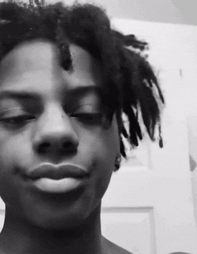 a black and white photo of a young man with dreadlocks on his head