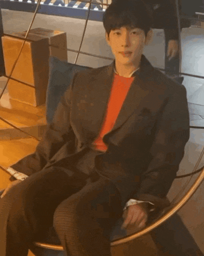 a man in a suit is sitting in a chair with his legs crossed .